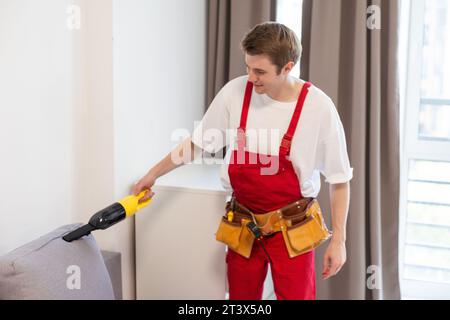 Lavoratore di sesso maschile che rimuove lo sporco dal divano con un  aspirapolvere professionale in ambienti interni Foto stock - Alamy