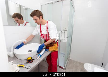 servizio idraulico. Ritratto idraulico vicino all'installazione del sifone del lavabo. Foto Stock