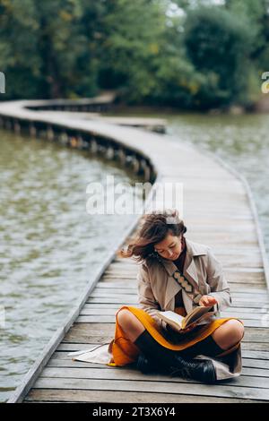 Donna che legge un libro su un lago in autunno a Praga Foto Stock