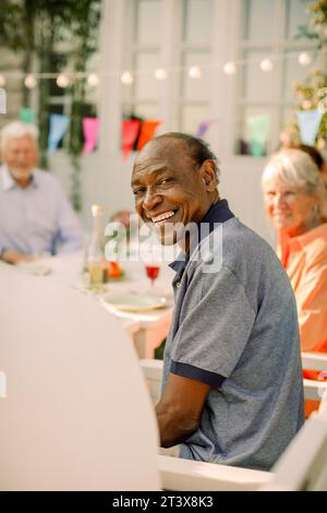 Ritratto di un anziano sorridente seduto sul cortile posteriore Foto Stock