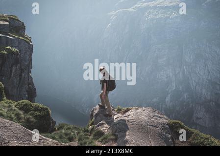 Escursionista in piedi sul bordo di una scogliera e godendo la vista Foto Stock