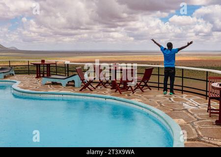 Un uomo vicino a una piscina in un punto panoramico in un Lodge al Tsavo East National Park, Kenya Foto Stock