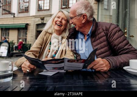 Coppia anziana allegra seduta con menu al caffè sul marciapiede Foto Stock
