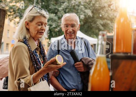 Donna anziana che sta esaminando il vaso mentre si trova accanto all'uomo al mercato Foto Stock