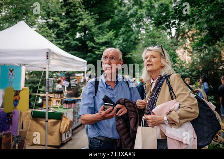 Un uomo e una donna anziani confusi che guardano lontano mentre si trovano al mercato Foto Stock