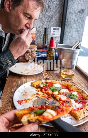 Pizza Margherita napoletana su un tavolo rustico in legno in una pizzeria tradizionale. Foto Stock