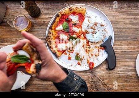 Pizza Margherita napoletana su un tavolo rustico in legno in una pizzeria tradizionale. Foto Stock