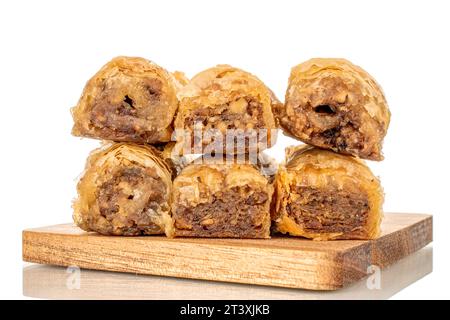 Diversi pezzi di dolce baklava su un tavolo da cucina in legno, macro, isolato su sfondo bianco. Foto Stock