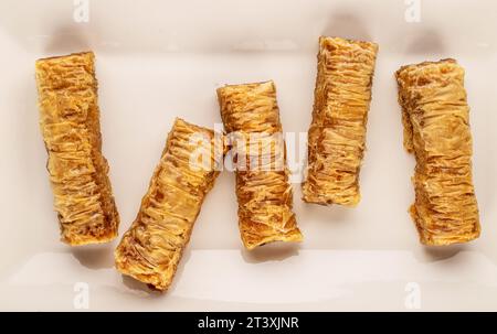 Diversi pezzi di dolce baklava su un piatto di ceramica bianca, macro, vista dall'alto. Foto Stock