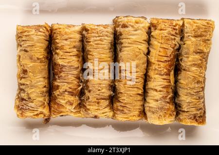 Diversi pezzi di dolce baklava su un piatto di ceramica bianca, macro, vista dall'alto. Foto Stock