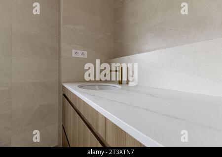 Immagine del bagno con piastrelle color crema e ripiano coordinato Foto Stock