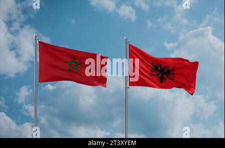 Le bandiere del Marocco e dell'Albania sventolano insieme al vento su un cielo nuvoloso e blu Foto Stock
