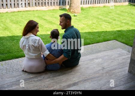 La famiglia felice si siede sulla terrazza di una casa di campagna Foto Stock