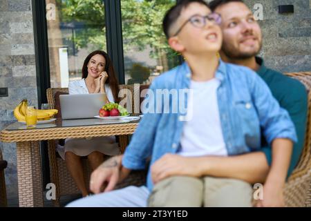 Il ragazzo siede in grembo ai suoi padri Foto Stock