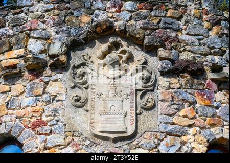 Scultura in pietra di uno stemma che decora un muro nel Puebloastur Eco-Resort Hotel & Spa. La località turistica si trova a Cofino, un piccolo villaggio rurale. Foto Stock