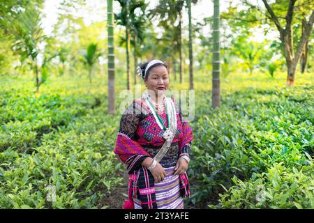 Donna della tribù Adi in abiti tradizionali adi in posa nel mezzo di una piantagione di tè, circondata da palme Assam nel nord-est dell'India Foto Stock