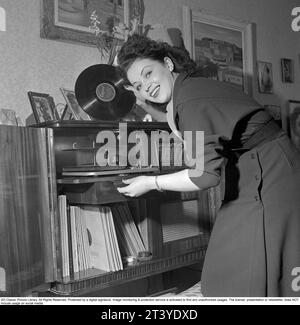 Donna in un grammofono negli anni '1950 Attrice Marion Sundh, 1927-1987 dal grammofono che è un modello di lusso combinato con una radio. I dischi erano fatti di materiale fragile e la velocità del disco di suonare come dovrebbe era di 78 giri al minuto. Svezia 1951. Rif. Conard 1689 Foto Stock