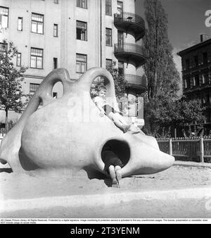 Parco giochi negli anni '1950 Due ragazzi stanno giocando in un parco giochi, arrampicandosi e seduti su una scultura di cemento dalle forme rotonde. Svezia 1951. Kristoffersson rif. BC47-12 Foto Stock