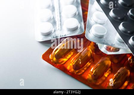 Primo piano di una pila di confezioni di diverse compresse e pillole su un tavolo bianco. Sfondo spazio copia isolato farmaco farmaceutico Foto Stock