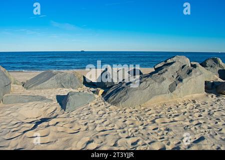 Piccole onde si tuffano in una spiaggia rocciosa di Sandy Hook, New Jersey, in una soleggiata giornata autunnale -14 Foto Stock
