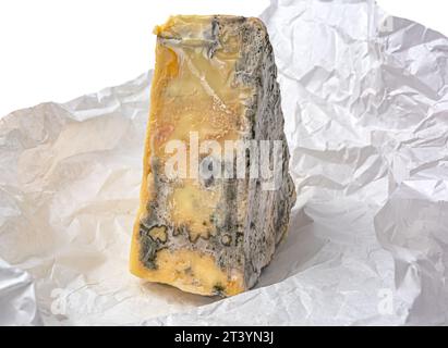 pezzo triangolare di formaggio con muffa su carta bianca a forma di primo piano Foto Stock