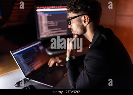 Lo sviluppatore mobile giovane scrive il codice di programma su un calcolatore, il programmatore lavora nell'ufficio domestico. Foto Stock