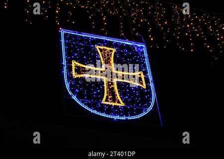 Stemma di Albisrieden, Zurigo (croce gialla con scudo blu) illuminato da luci natalizie su sfondo nero (Zürich, Svizzera) Foto Stock