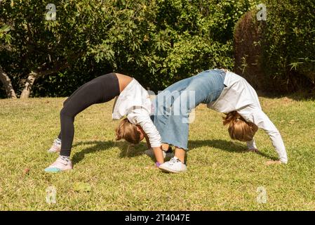 Due ragazze nel parco che fanno esercizi acrobatici. Bambini che giocano all'aperto e praticano attività di ginnastica. Vita sana e nutrizione in yout Foto Stock