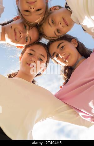 Cinque amici si sono rannicchiati in cerchio, guardando la telecamera e sorridendo. Amicizia e unità tra le ragazze. Amici per sempre. Adolescenza e pubertà Foto Stock