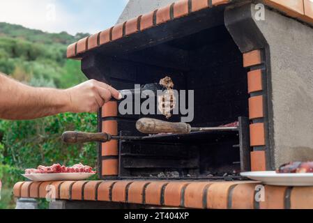 Togliere la carne cotta da un barbecue, pronta per mangiare. Grigliare lombate di maiale e costolette in giardino, in un giorno festivo con gli amici Foto Stock
