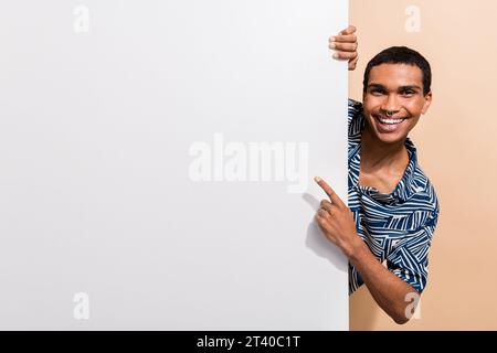Foto di una camicia con stampa attraente e carina con il dito che punta lo spazio vuoto sfondo di colore beige isolato Foto Stock