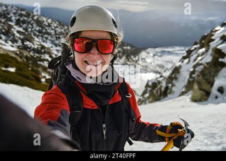 Alpinista che scatta selfie su un terreno innevato durante le escursioni Foto Stock