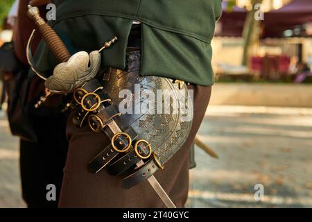 Vecchia spada da soldato su un costume medievale da cavaliere. Rievocazione storica di un'arma. Foto Stock