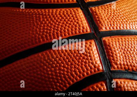 Vista macro della superficie da basket in pelle testurizzata. Streetball e canestro. Modelli e sfondi sportivi. Ombre e luci Foto Stock