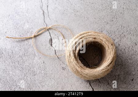 Un rotolo di filo rustico su sfondo grigio sassoso. Vista dall'alto. Foto Stock