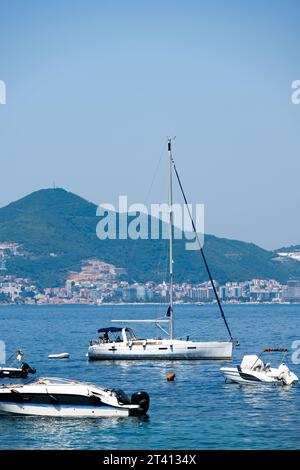 Yacht in Montenegro con vista sulla vecchia Budva nel mare Adriatico nelle giornate di sole. Barche bianche nel Mar Mediterraneo con le montagne Foto Stock