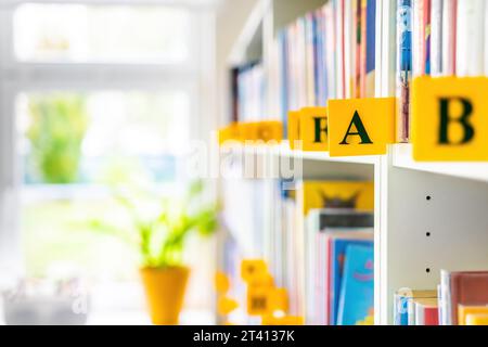 Libri sugli scaffali della biblioteca. Autori di libri inseriti per alfabeto. Foto Stock