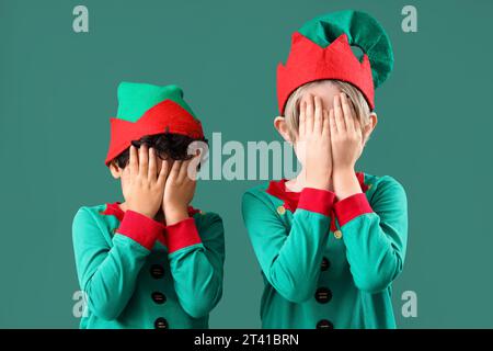 Simpatici bambini in costume da elfi che chiudono gli occhi su sfondo verde Foto Stock