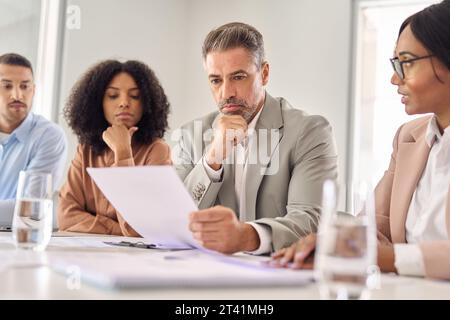 Uomo d'affari serio che controlla i documenti legali durante una riunione di consulenza legale. Foto Stock