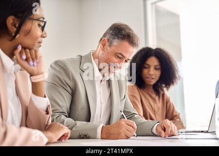 Buon vecchio uomo d'affari che firma un documento d'affari legale alla riunione del Consiglio. Foto Stock