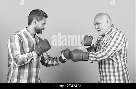 uomini di boxe di due generazione isolati sul giallo. uomini di generazione boxe in studio. Foto Stock