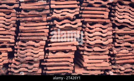 vista laterale di vecchie tegole per tetti usate impilate, sfondo astratto di tegole rosse scartate disposte, realizzate in argilla naturale e di lunga durata Foto Stock