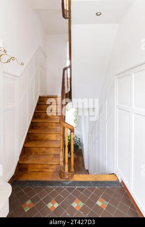 Una parete di mattoni bianchi con una scala a chiocciola che conduce ad un ingresso ad arco Foto Stock