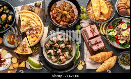 Assortimento di piatti francesi su sfondo scuro. Concetto di cucina tradizionale. Vista dall'alto. Foto Stock