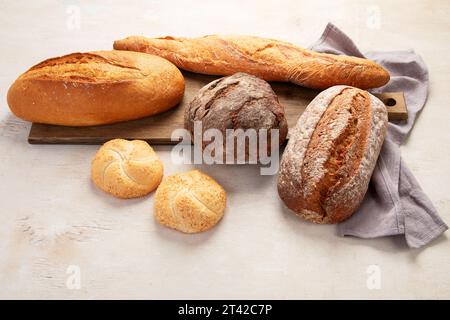 Assortimento di vari tipi di delizioso pane appena sfornato su sfondo bianco, vista dall'alto. Foto Stock