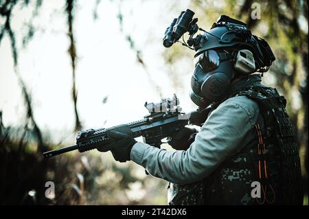 Viene raffigurato un uomo in maschera antigas con equipaggiamento militare completo, che indossa un casco e tiene in mano un fucile Foto Stock