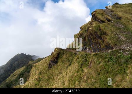 Due viaggiatori si trovano su una tortuosa strada di montagna che si affaccia su un vasto paesaggio sottostante Foto Stock