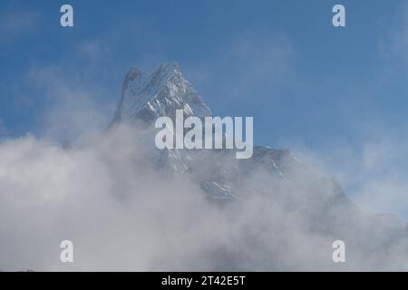 Una vista aerea di un aereo che sorvola una catena montuosa innevata, con meravigliosi cieli blu sullo sfondo Foto Stock