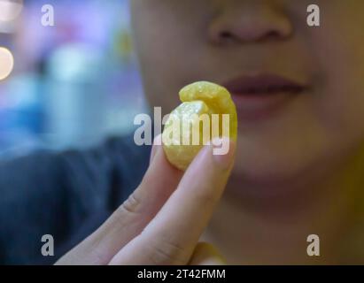 La donna tiene croccanti croccanti croccanti di maiale che sta per mangiare. E' un popolare cibo di strada che è delizioso e che si trova comunemente in paesi asiatici come Foto Stock