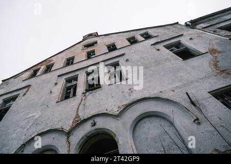 Dalla facciata sottostante di un vecchio edificio residenziale con finestre di vetro rotte contro il cielo senza nuvole Foto Stock